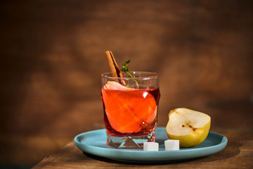 homemade hot mulled pear cider with a cinnamon stick on a wooden background