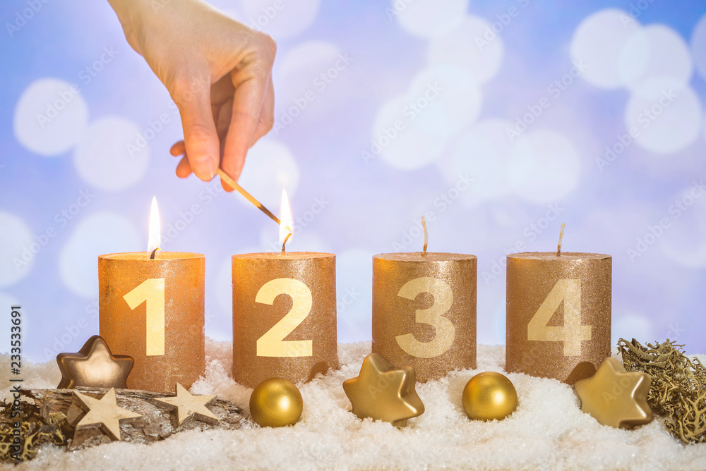 Wall mural Two advent candles in snow lit by match in hand