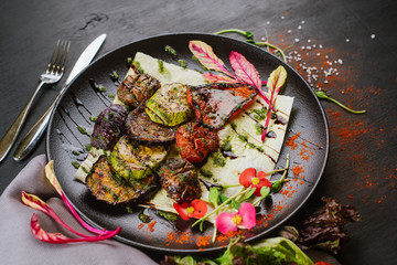 Vegan dish with roasted vegetables on black background