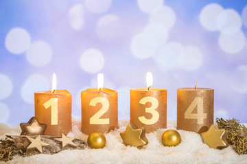 Three golden advent candles lit in snow