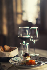 smoked salmon with cheese, onion and herbs served on plate with glass of wine and toast, modern gastronomy