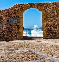 old door in stone wall towards the sea
