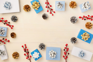 Christmas composition of fir cones, gift boxes and red berries, laid out in a circle. Copy space on a light wooden background.