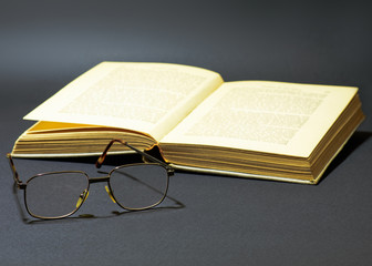 Reading glasses next to an old book