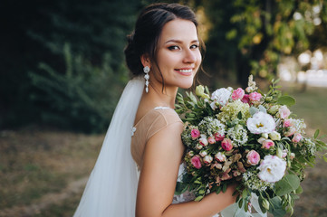 A beautiful bride stands on nature in greenery with a large bouquet. Wedding portrait close-up of the young bride. Wedding photography. - Powered by Adobe