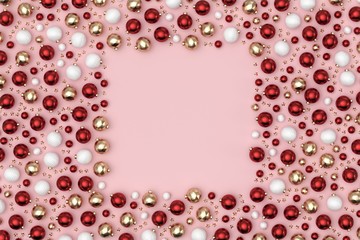 Minimal christmas background composition. Scattered red, gold, white decoration balls and stars on pastel pink background with a square note space. 3D rendering.