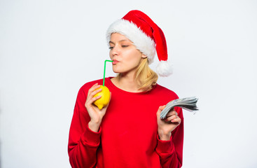 Girl santa hat drink juice lemon straw while hold pile of money. Symbol of wealth and prosperity. Christmas wishes. Rich girl with lemon and money. Woman lemon millionaire. Lemon money concept