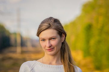 Portrait of an attractive young blonde with blue eyes on nature background