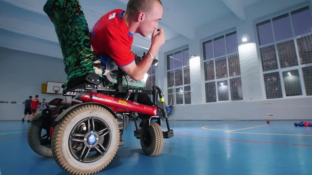 A disabled man in a wheelchair enjoying playing boccia. Playing in the gym
