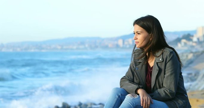 Relaxed teenage girl looking at horizon on the beach with the sea in the background