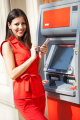 Fototapeta na wymiar Happy woman withdrawing money from credit card at ATM