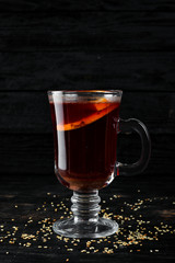Hot wine with citrus fruit. Winter and autumn traditional cocktails. On a black wooden background. Free copy space. Top view.