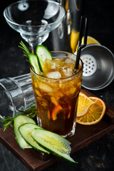 Tasty alcoholic cocktail. Cola, whiskey, cucumber and ice. On a wooden background. Top view.