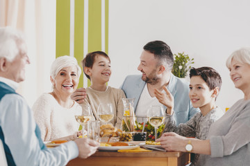Happy boy between parents during family dinner with smiling grandmother