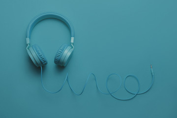Blue headphones on blue background. Music concept