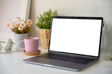 Blank screen laptop with home office supplies on desk.