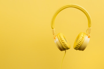 Yellow headphones on yellow background. Music concept.