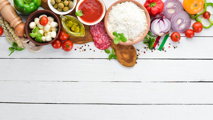 Ingredients for pizza. Mushrooms, sausages, tomatoes, vegetables. Top view. On a white wooden background. Free copy space.