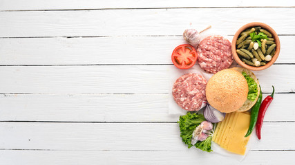 Preparation of burger. Meat, tomatoes, onions. On a white wooden background. Top view. Free copy space.