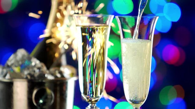 Still-life with a bottle of champagne and glasses. Behind the flashing lights and sparklers of the Christmas holiday.  4K video.