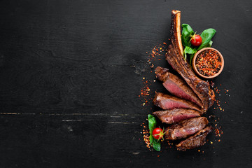 Steak on the bone. tomahawk steak On a black wooden background. Top view. Free copy space.