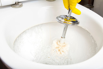 The cleaner in the bathroom washes the toilet with a brush. Close up.
