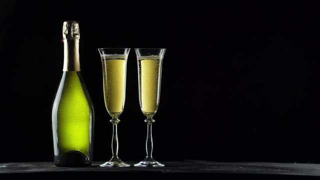 
Still-life with a bottle of champagne and glasses. Black background. 4K video.
