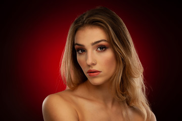 Fototapeta premium Beauty portrait of a beautiful young woman with brown long hair over dark red background