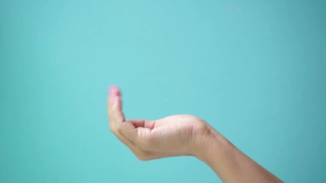 Closeup side view of one beautiful adult female cupped hand with pink manicure holding or showing something virtual and invisible isolated on green background. Real time full hd video footage.