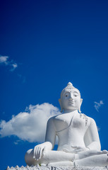 White Buddha sitting on top of a mountain against the background of a bright summer sky in the city of Pai in the north of Thailand. Asia travel