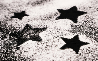 Print of stars on a black surface dusted with flour