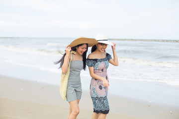 two young asian women walking on the tropical beach