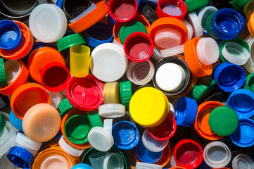 Pile of brightly colored plastic bottle tops gathered on the beach to highlight the crisis of...