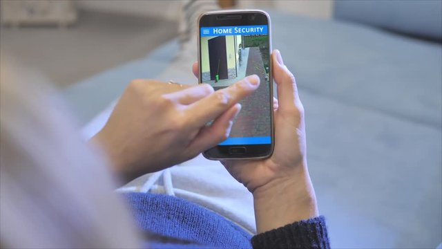 woman monitoring home video surveillance on smartphone mobile application