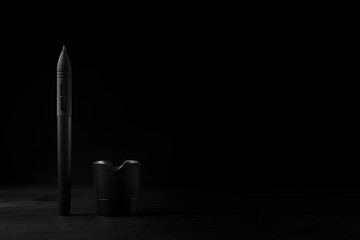 Graphic tablet pen for illustrators and designers on black wooden background.
