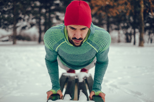 Man doing push ups on park bench in the snow
