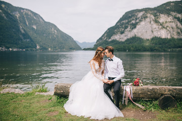 A wedding couple sits on the shore of a lake in the fairy-tale town of Austria, Hallstatt.