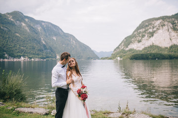 Fototapeta na wymiar A wedding couple on the background lake and mountains in the fairy-tale town of Austria, Hallstatt.