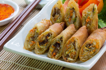 Deep fried spring rolls, Por Pieer Tod or Fried spring rolls (Thai Spring Roll) on white dish on wooden table,Thai and Chinese people.