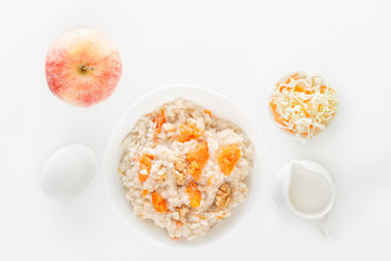 Oatmeal with pumpkin and nuts, salad, egg and a jug of milk on a white background. View from above. Copy space.