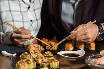 Fotobehang Partial view of people eating sushi rolls in restaurant © LIGHTFIELD STUDIOS