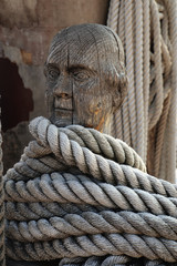 Ropes around a head shaped wooden cleat on an old vessel