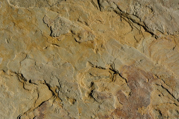 Natural stone with a natural texture as a design concept. Cracks created by nature on the surface of the stone with a natural color scheme, create a natural textured background. Texture for design.