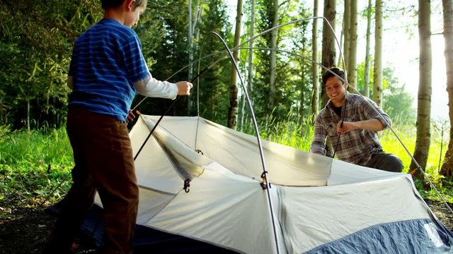 American Caucasian father and son erecting tent together on vacation outdoor