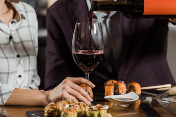 Cropped view of man pouring red wine in glass in restaurant
