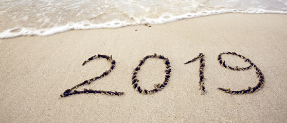 Year 2019 written at the caribbean sand beach with sea wave .