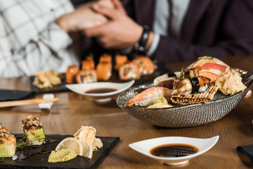 Sushi rolls and seafood on the background of couple holding hands