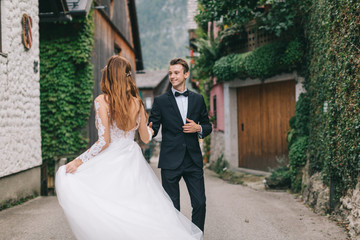 A beautiful wedding couple walks in a fairy Austrian town, Hallstatt.