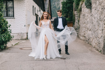 A fun wedding couple joking each other and walks in a fairy Austrian town, Hallstatt.