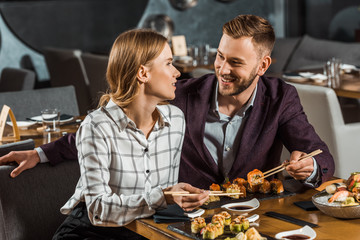 Attractive smiling couple amorously looking at each other while having dinner in restaurant